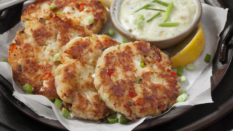 Plated crab cakes with tartar sauce and a lemon wedge