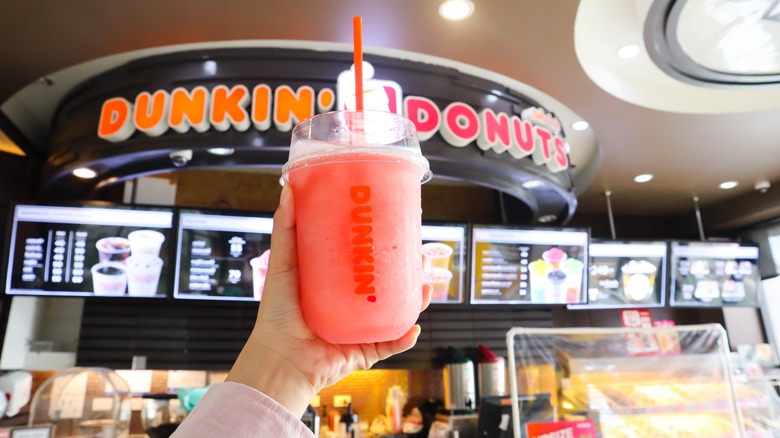 hand holding Dunkin' strawberry drink 