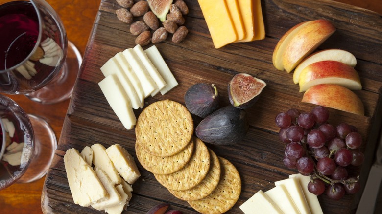 cheese board with apples, figs, and grapes