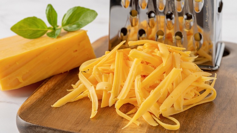 Shredded cheddar next to a grater
