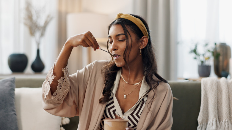 Woman in robe eating pint of ice cream at home