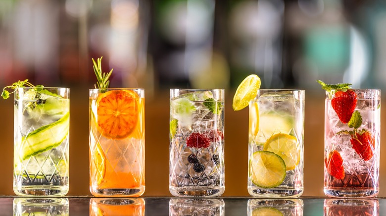 Five fruity highball drinks on a table