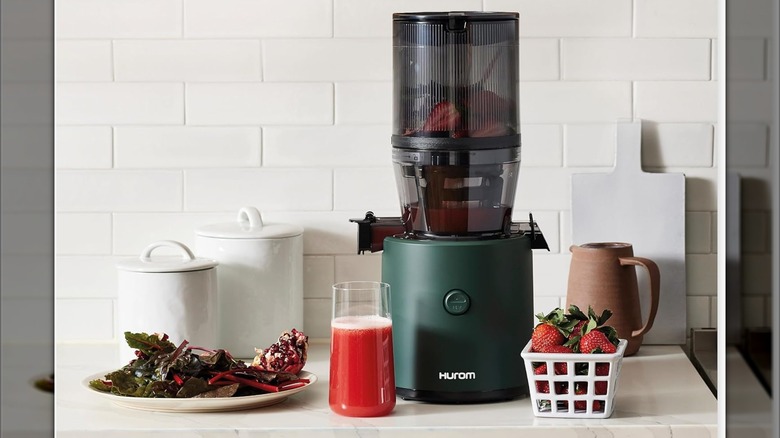 Hurom H320 Slow Juicer on a kitchen counter with fruits and juice