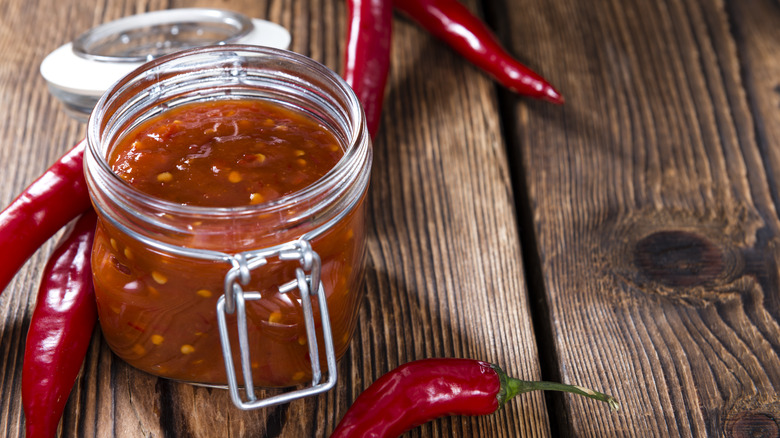 Jar of chili paste and fresh peppers.