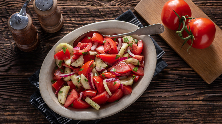 Bowl of tomato cucumber salad on cutting board