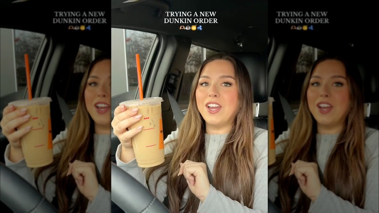 Person holding Dunkin' coffee in a car