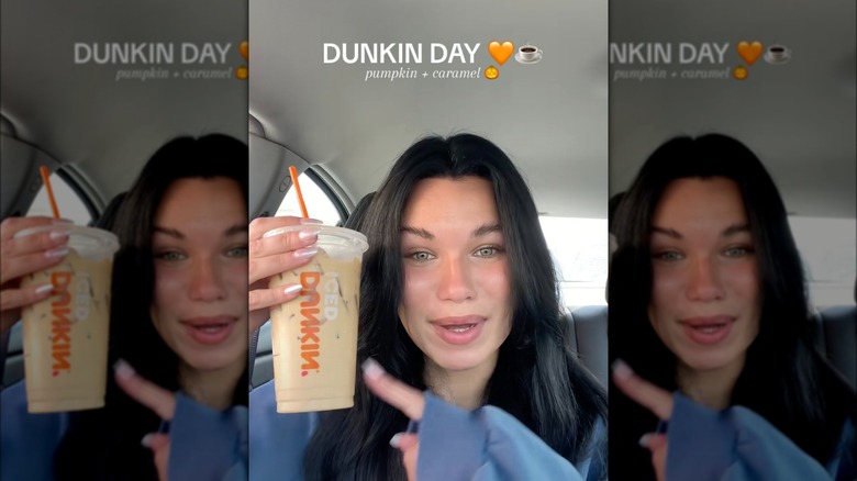 Person holding Dunkin' drink in a car