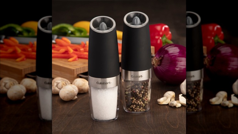 Gravity salt and pepper grinders in front of vegetables