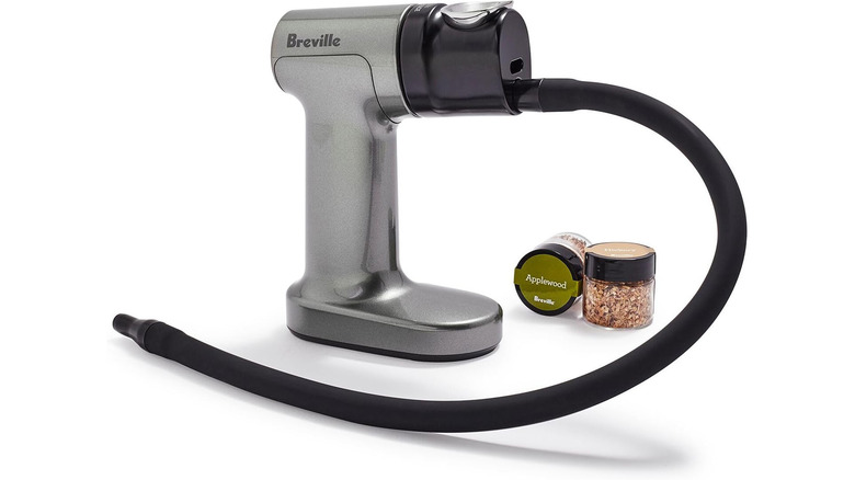 A product image of a Breville smoking gun next to two containers of wood chips