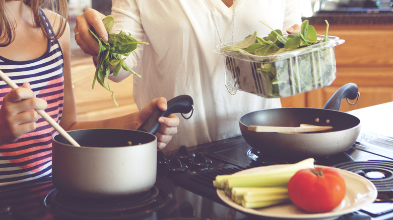 adding spinach to pot of soup