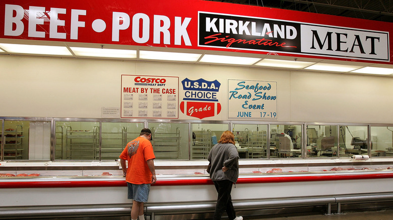 Two people standing in front of the Costco meat department