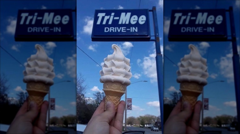 Hand holding ice cream cone under Tri-Mee Drive In sign