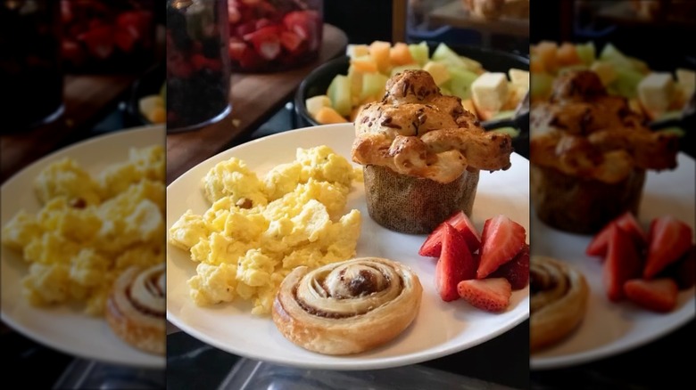 Breakfast pastries, scrambled eggs, and fruit on white plate at French Quarter Inn breakfast buffet