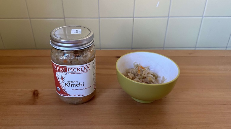 Real Pickles kimchi in jar on table next to bowl of kimchi