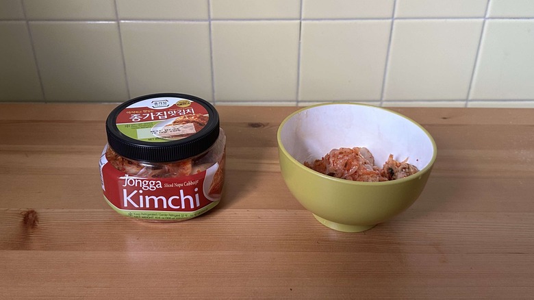 Container of Jongga cabbage kimchi next to bowl of kimchi