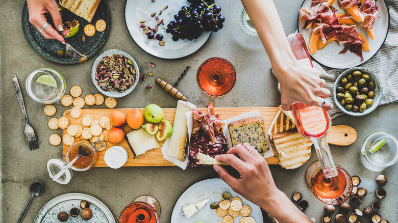 People reaching over charcuterie board