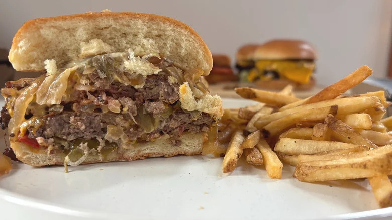 The Bacon Smashed Hatch Chile burger cut in half next to a pile of fries