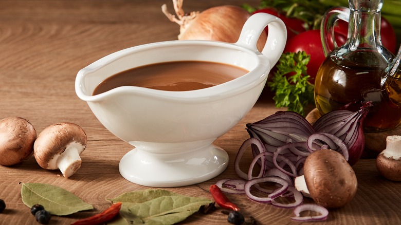 boat of brown gravy surrounded by aromatic ingredients