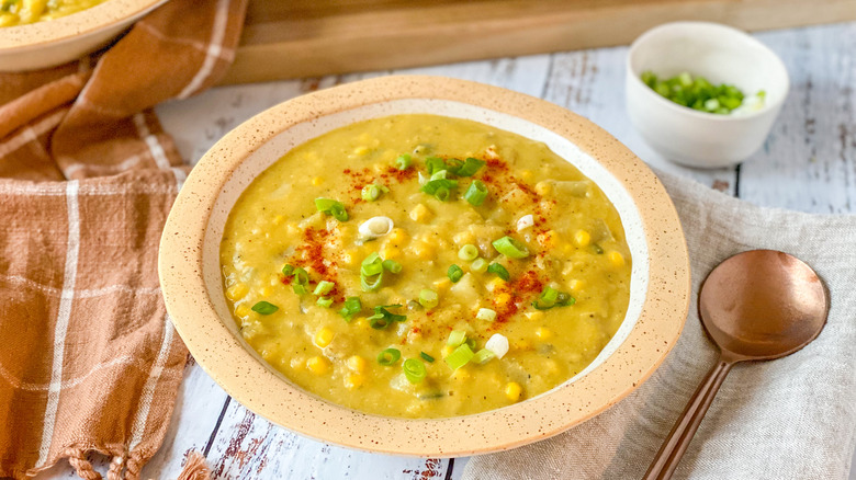 Vegan corn chowder with scallions next to spoon