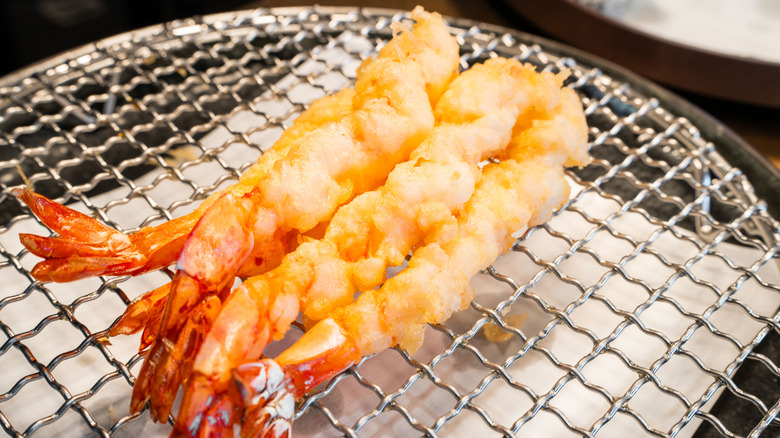 Shrimp tempura dripping oil from cooling rack