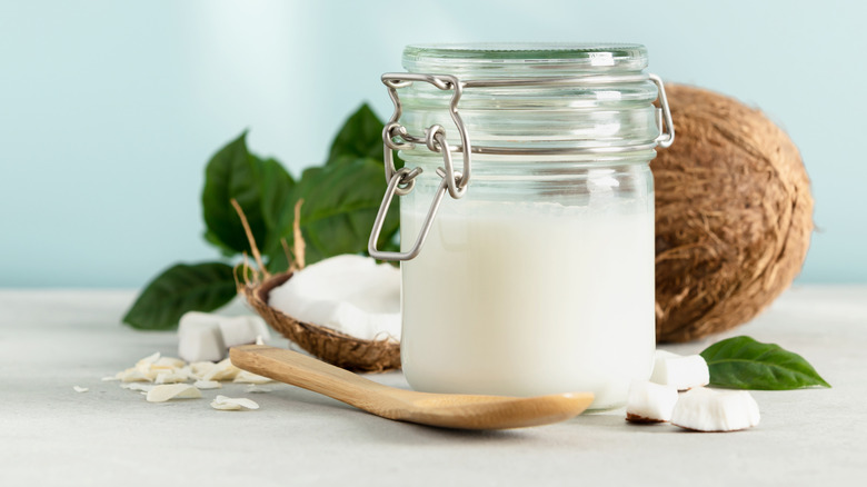 jar of coconut oil in front of a sliced coconut