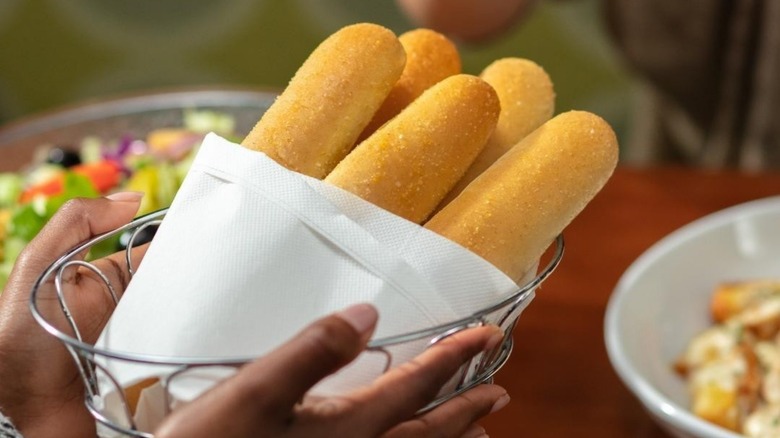 person holding basket of breadsticks in Olive Garden