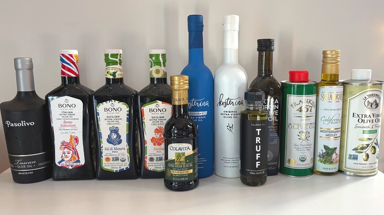 12 bottles of olive oil lined up on white background