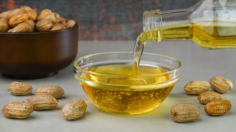 pouring peanut oil into bowl surrounded by peanuts