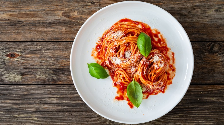 Pasta with marinara sauce and basil in a white bowl