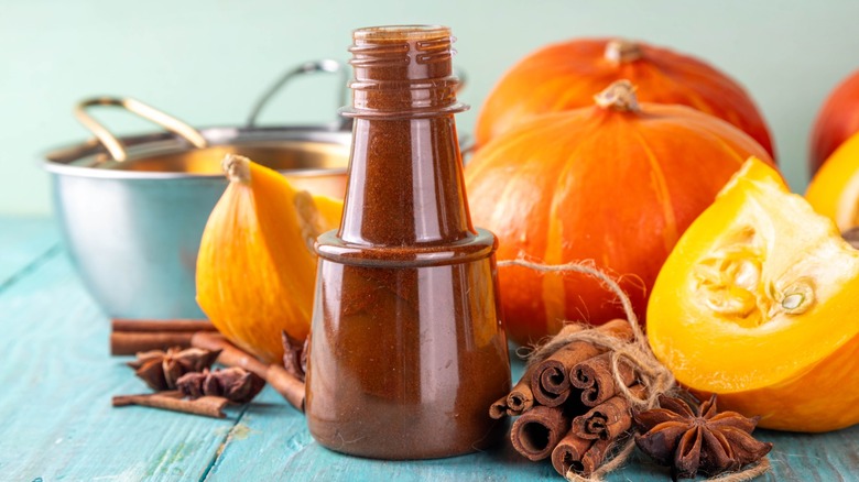 Glass jar of homemade pumpkin spice syrup with ingredients