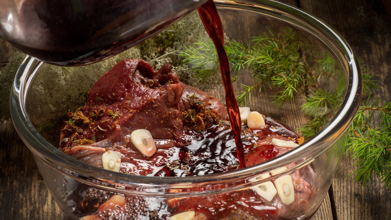 pouring red wine into beef marinade