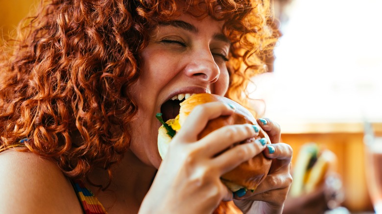 Happy person eating a fast food burger