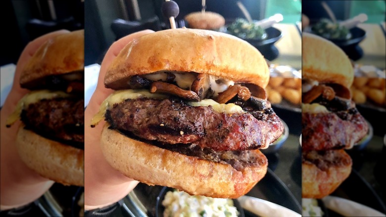 Hand holding large cheeseburger