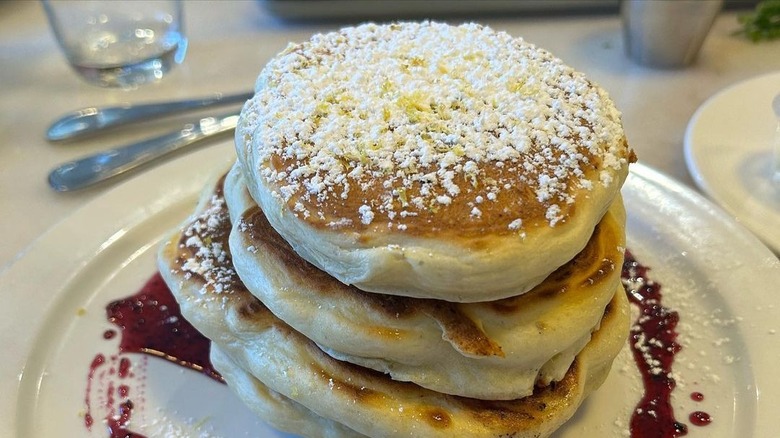 stack of pancakes with powdered sugar on white plate