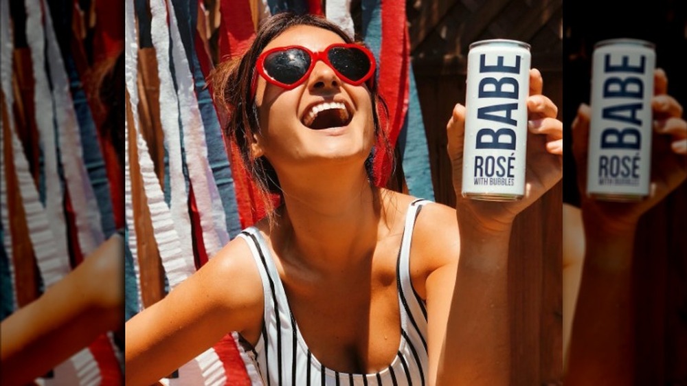 A girl with red sunglasses holding a can of BABE rose