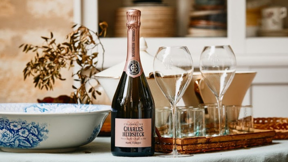 A bottle of rose champagne on a table with two wine glasses