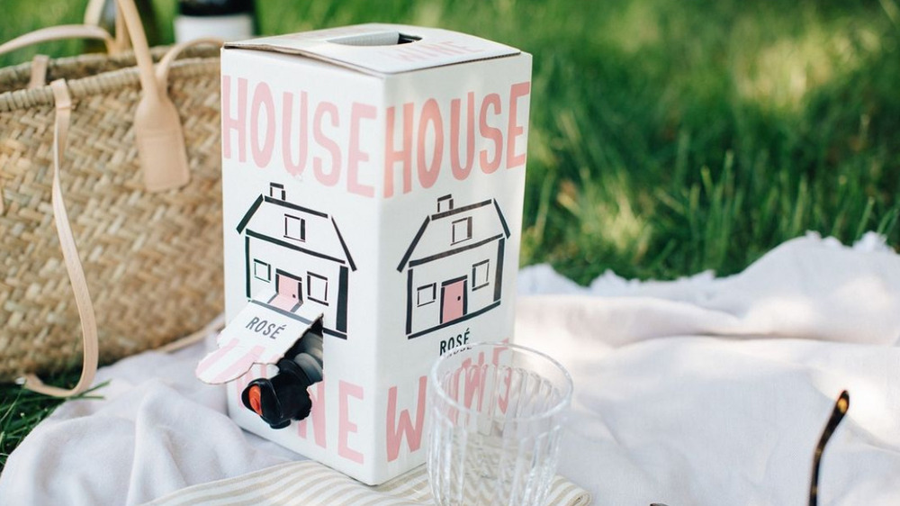 a box of rose house wine sitting on a blanket in the grass