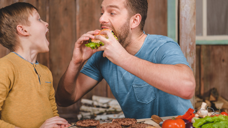 Adult and child eating hamburgers outside