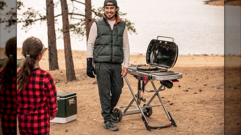 Weber Traveler Portable Gas Grill outside by a lake with two people