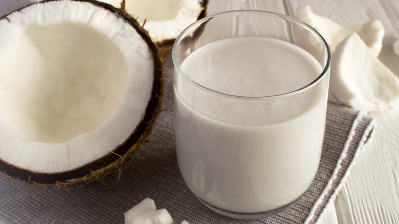 Glass of coconut milk beside shell