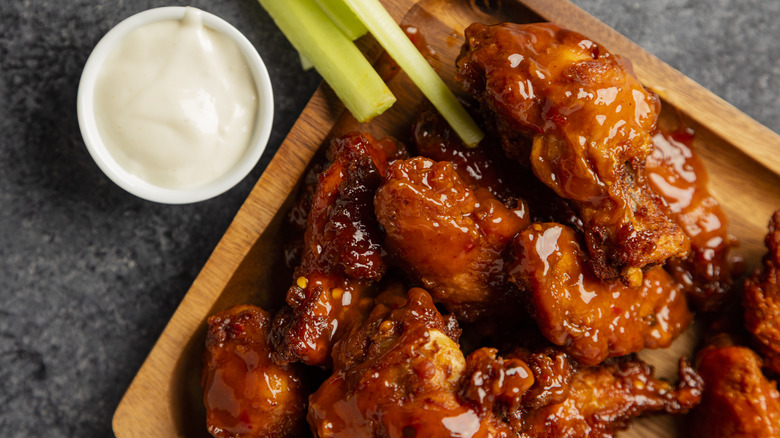 A board of juicy chicken wings next to a ramekin of ranch