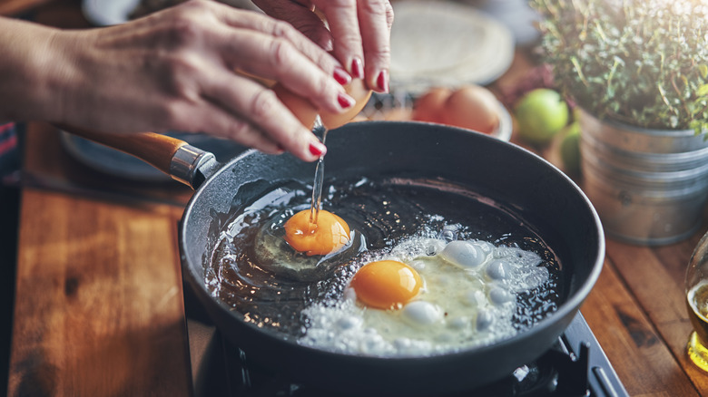 Hands frying eggs in a pan