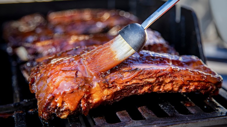 Ribs brushed with barbecue sauce on grill