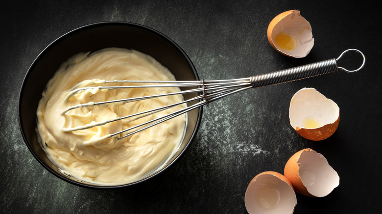 bowl of mayonnaise, egg shells, with whisk