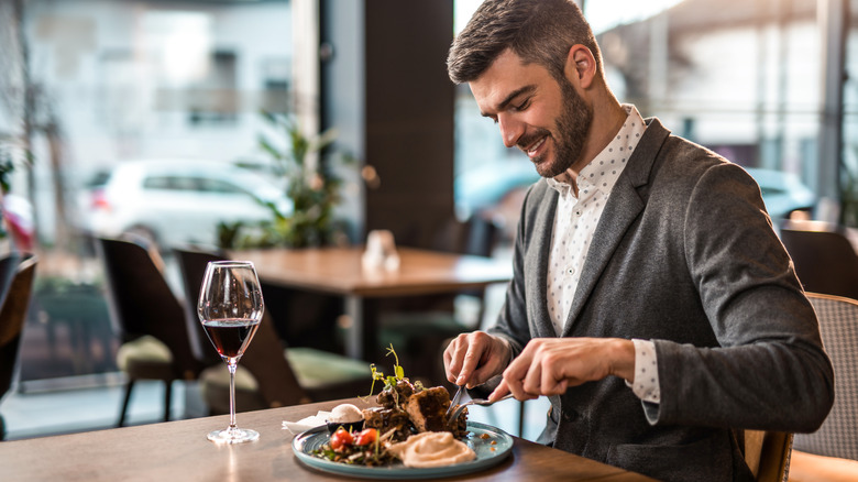 Man cutting into a dish alone at restaurant