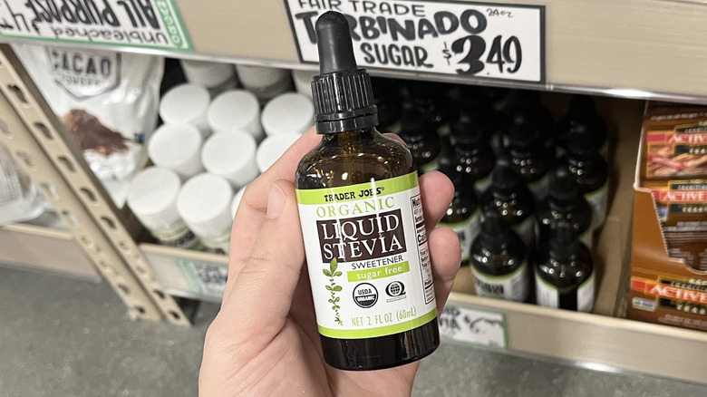 Hand holding Trader Joe's liquid stevia bottle in store aisle