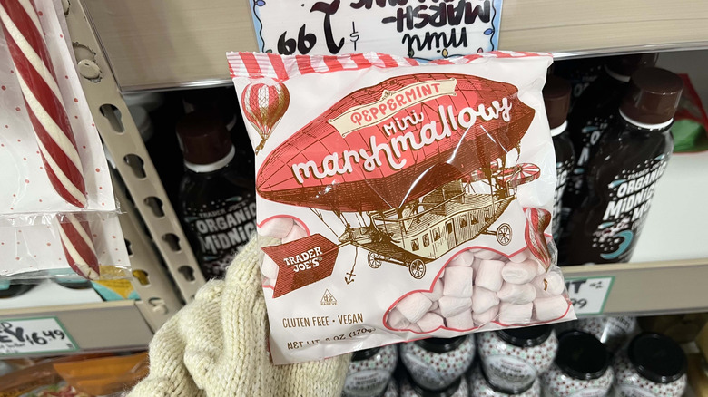 Hand holding bag of Trader Joe's peppermint marshmallows in store aisle