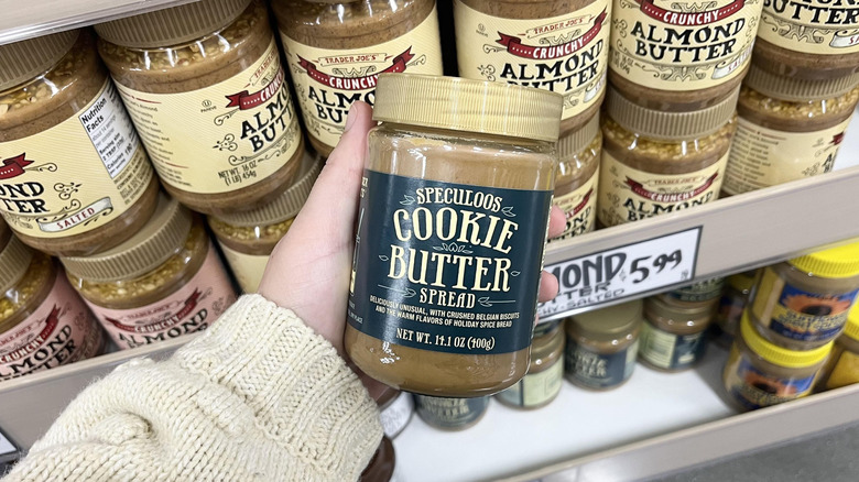 Hand holding Trader Joe's cookie butter jar in store aisle