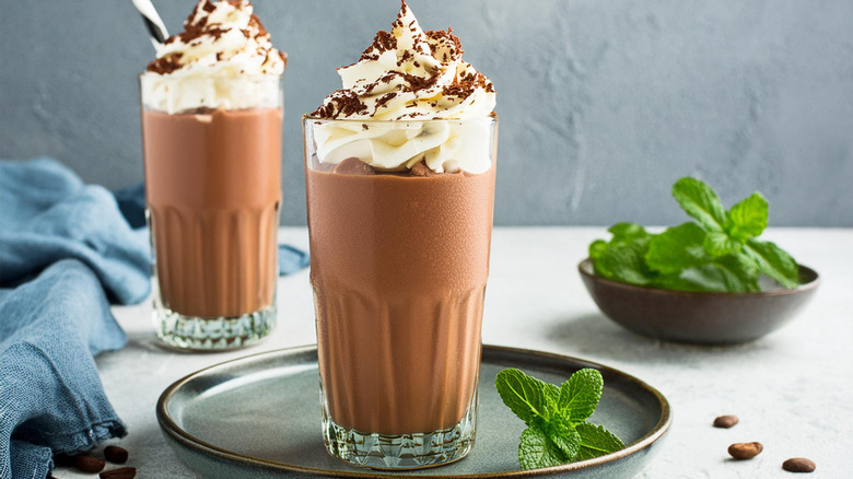 Two chocolate milkshakes topped with whipped cream