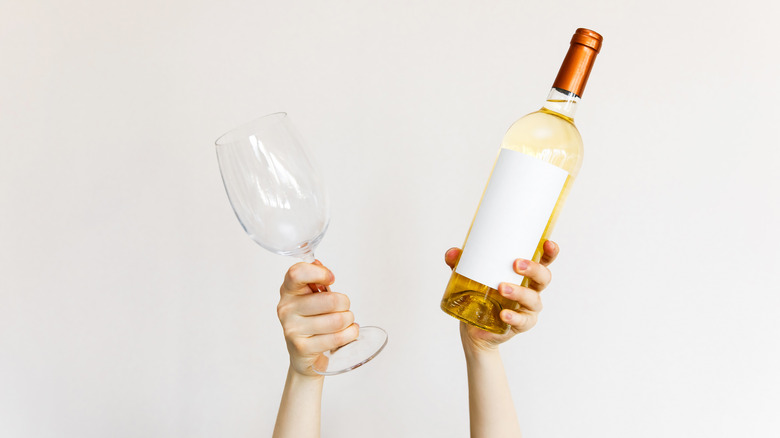 hands holding white wine bottle